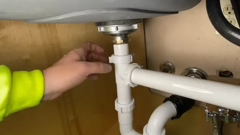 Under-sink cabinet open showing P-trap drain and hot and cold supply valves inspected for leaks in Commerce City