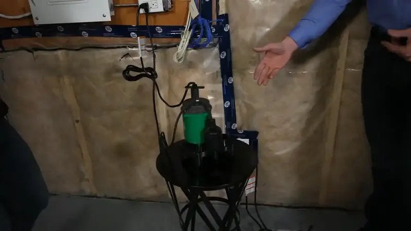 Sump pump in a basement pit with discharge pipe and check valve inspected in a Commerce City Adams County home