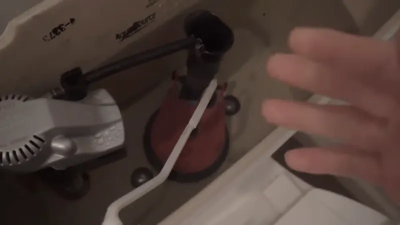 Inside of a toilet tank in a Commerce City home showing the flapper and fill valve components that cause a running toilet